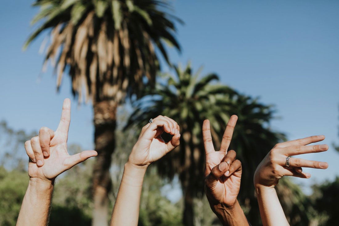 cuatro manos de personas de diferentes países con una letra cada una mostrando la palabra "love"